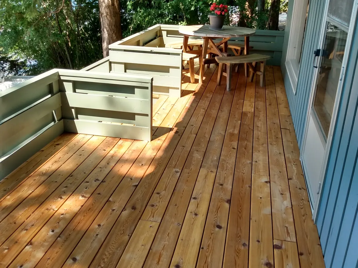 Stained cedar deck with painted green railings and a table at the far end